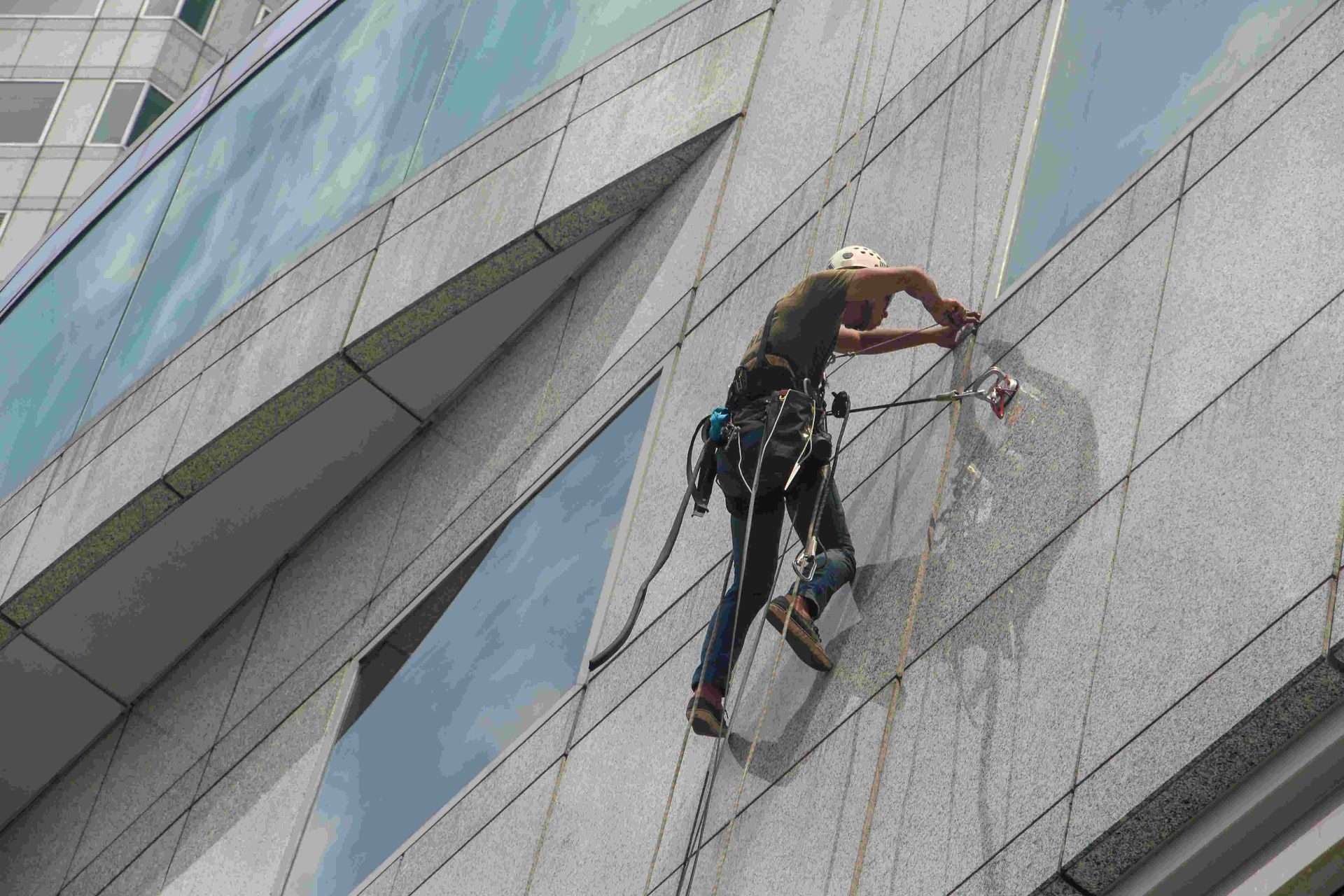 Worker cleaning high-rise windows with safety gear