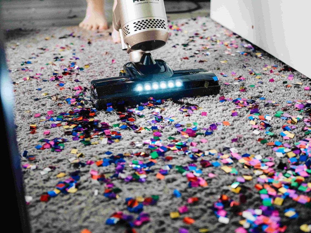 Vacuuming colourful confetti scattered on carpet