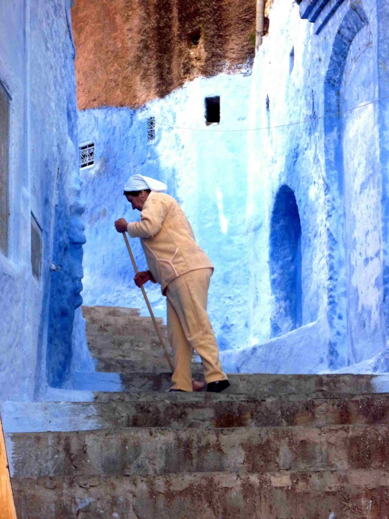 Person sweeping steps in blue alley