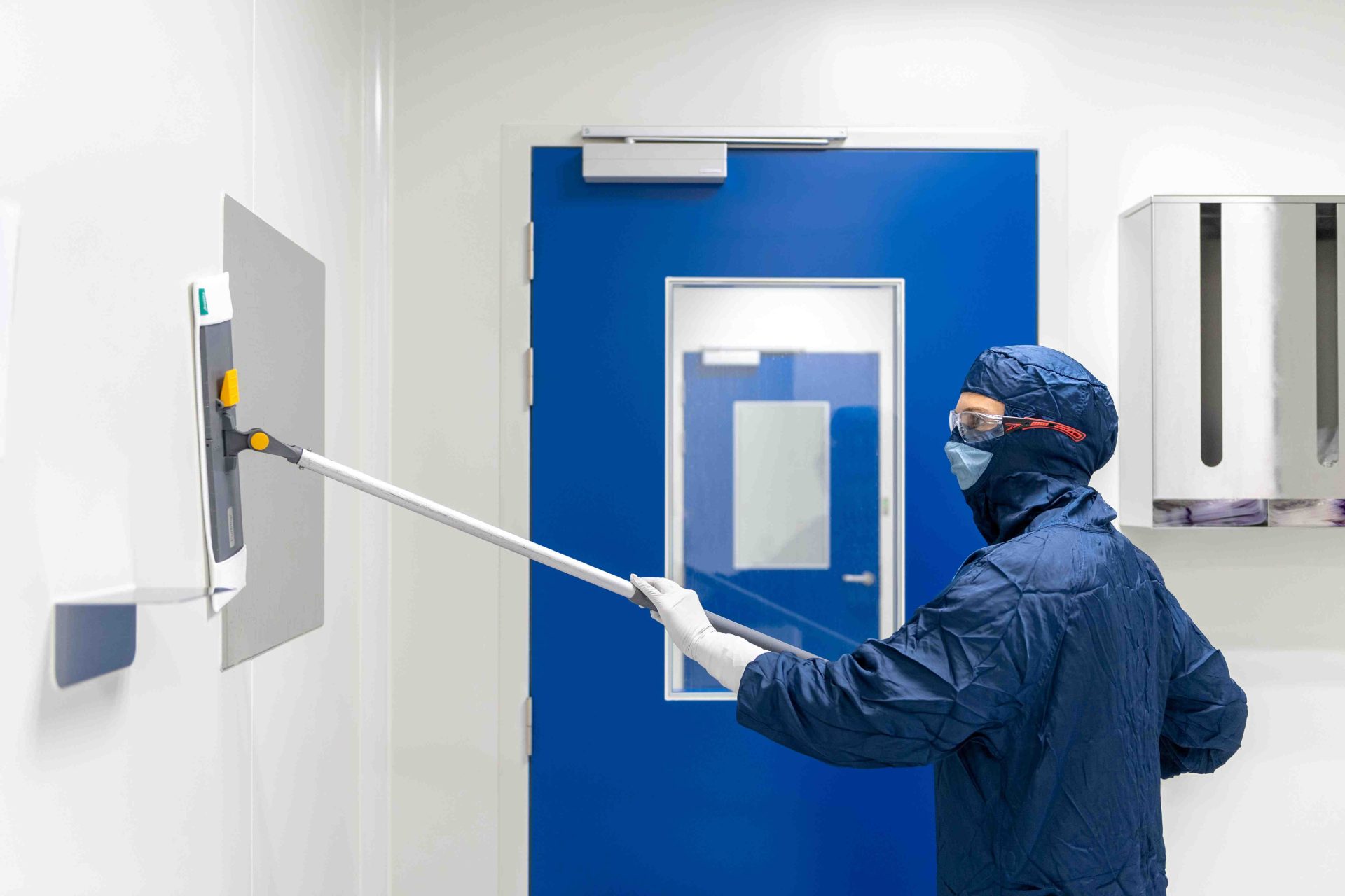 Worker in cleanroom wiping walls meticulously